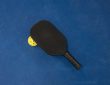 Black pickleball paddle resting on a yellow pickleball on a blue surface